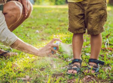 A parent spraying bug spray on their child to help keep mosquitoes away