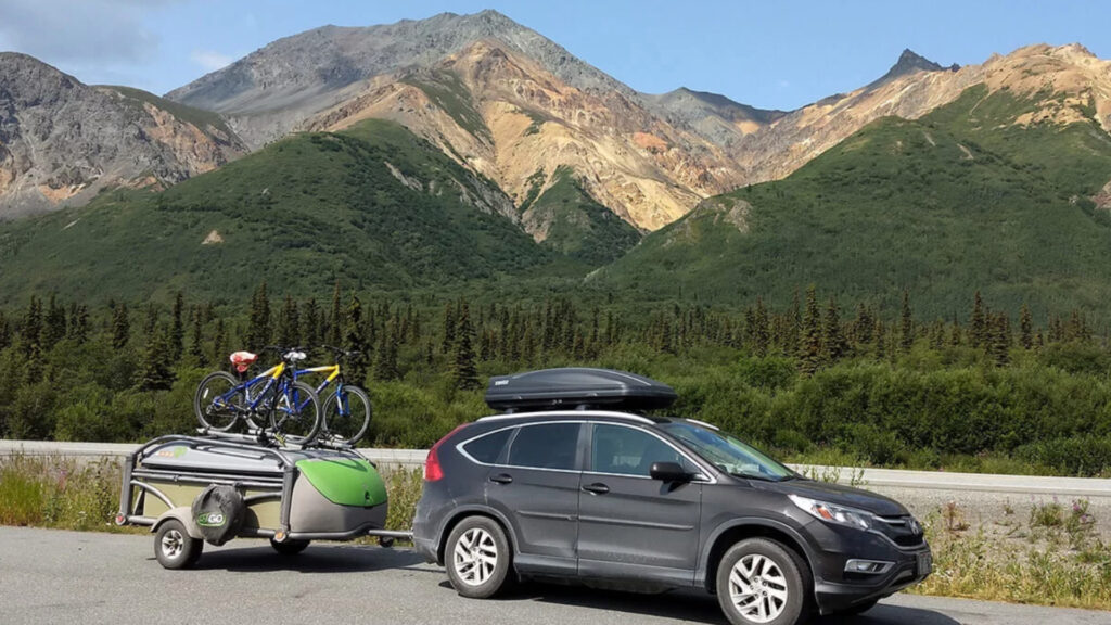 A SylvanSport trailer attached to an SUV by the mountains