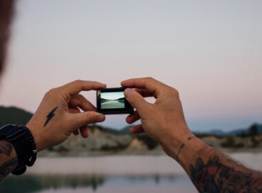A man taking a photo, showing his camping tattoos on his arm