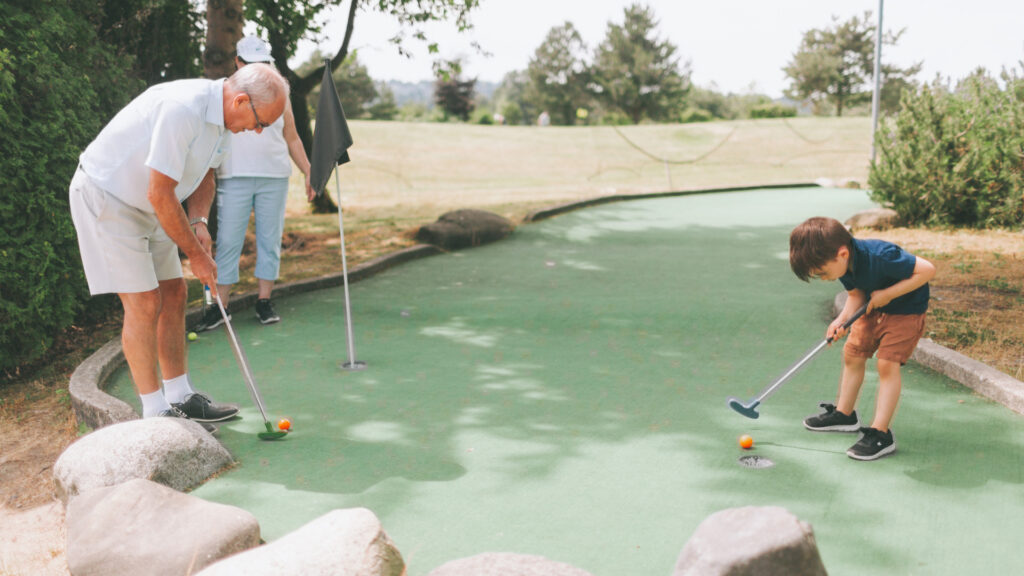 A child playing mini golf with his parent at a good sam club campground