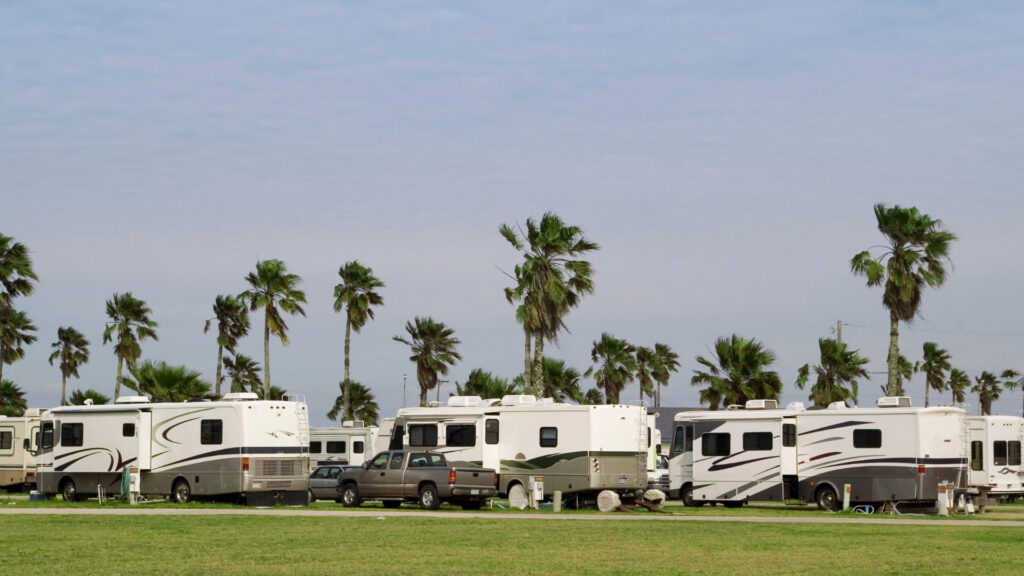 RVs parked in a RV lot at an RV park by palm trees