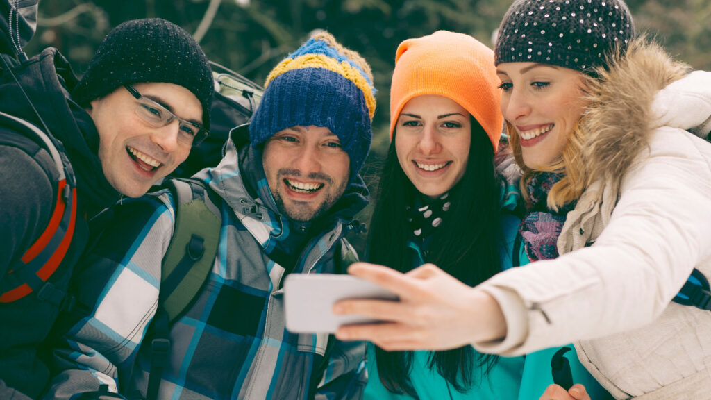 A group of friends taking a selfie while out camping in the winter, dressed in layers after following these camping tips