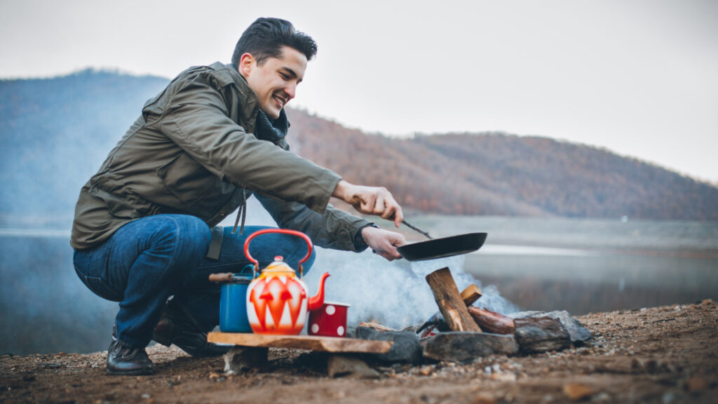 A man cooking himself food while camping in the winter, following winter camping tips