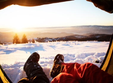 A couple laying in a sleeping tent after following winter camping tips to prepare for their trip