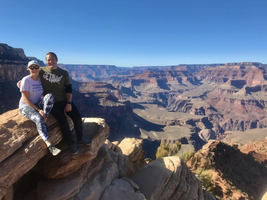 Us sitting on a rock with the vast Grand Canyon behind us 