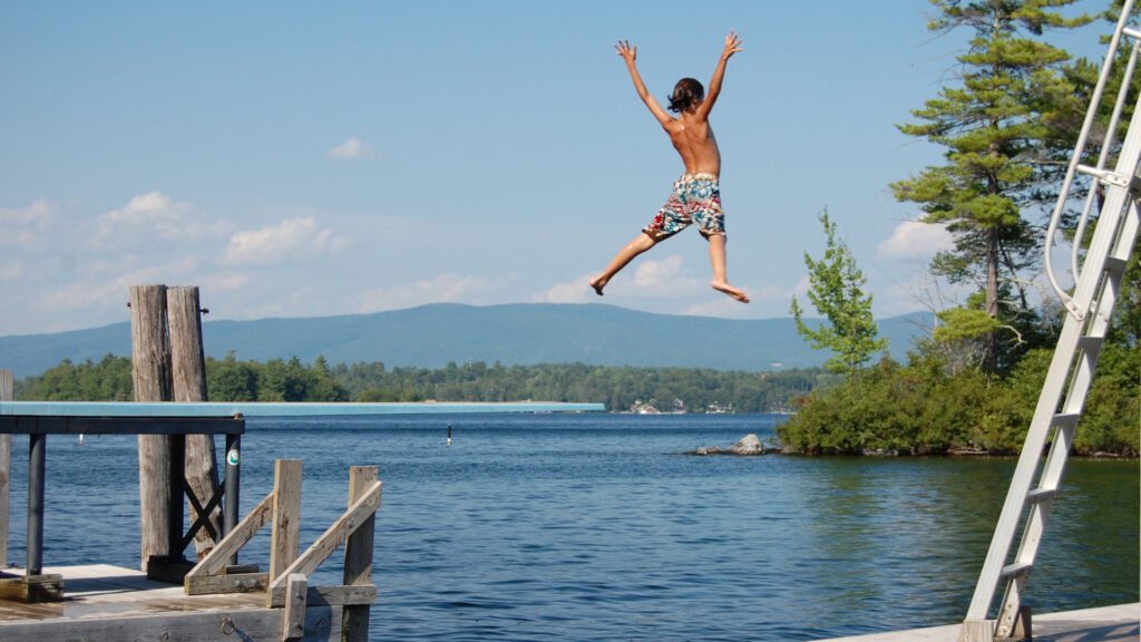 A boy jumping into lake winnipesakuee by his campground