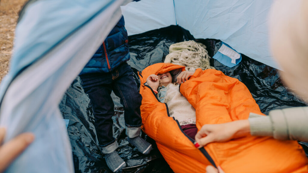 A kid playing in his sleeping bag from his camping gift basket