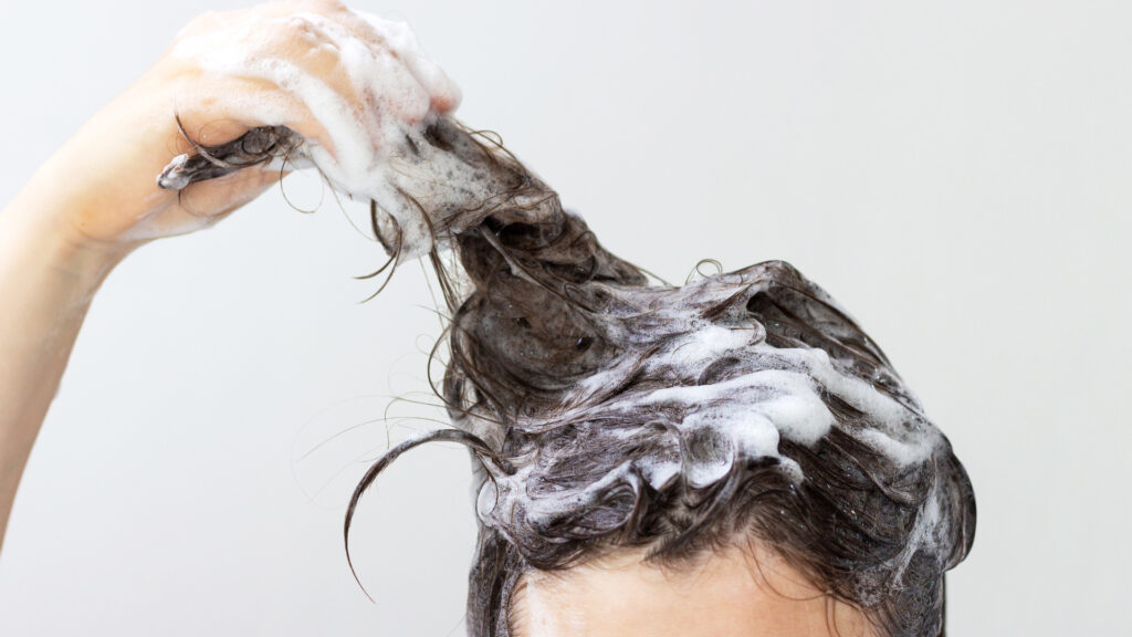 A person washing their hair after figuring out how to get smoke smell out of hair
