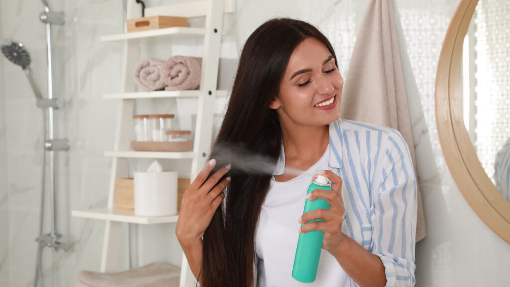 A woman using dry shampoo after figuring out how to get smoke smell out of hair