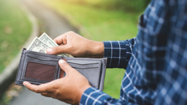 A man opening his wallet at a campground to pay extra due to inflation