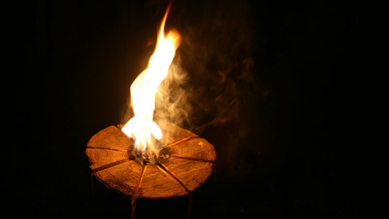A lit swedish fire log at night