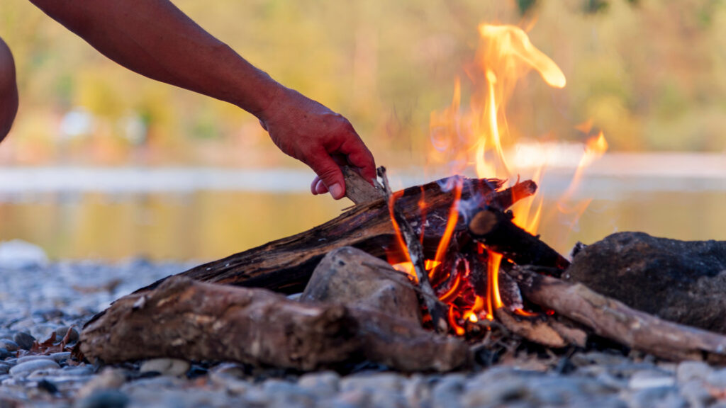 A person starting a fire following five rules for the perfect campfire