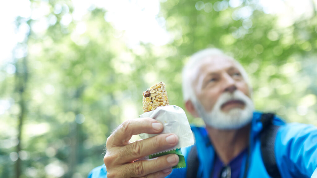 A man eating a granola bar, a popular hiking snack