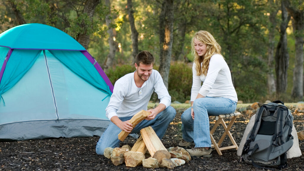 A couple building a campfire outside their tent