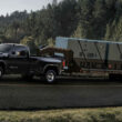 A GMC Sierra HD SLE on the road towing a trailer. This truck has a towing capacity of up to 18,500 pounds