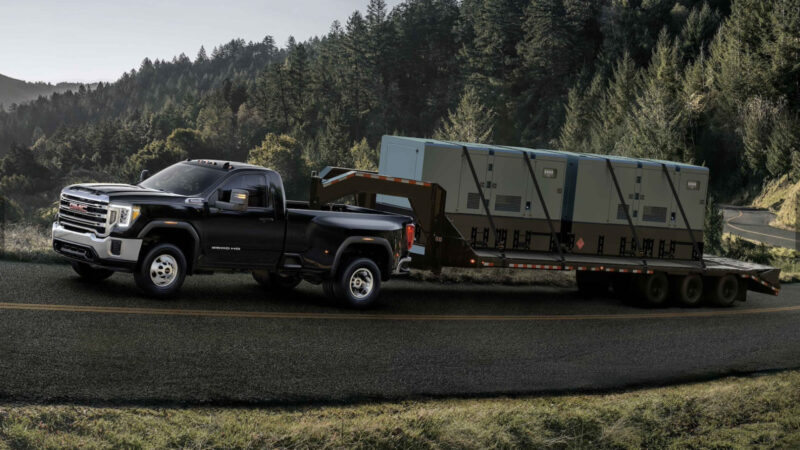 A GMC Sierra HD SLE on the road towing a trailer. This truck has a towing capacity of up to 18,500 pounds