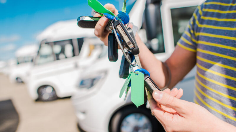 A person holding the keys to their new RV at an RV lot