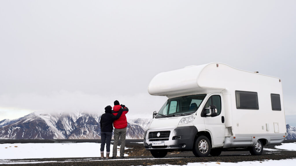 A couple standing next to their RV in the snow with slide toppers