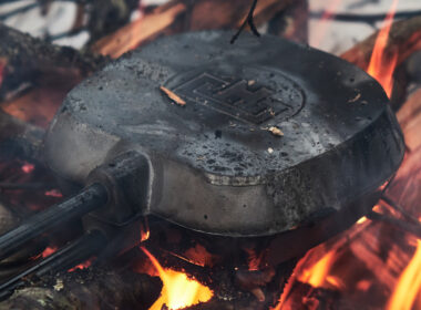 A pie iron being used to make a recipe over a campfire