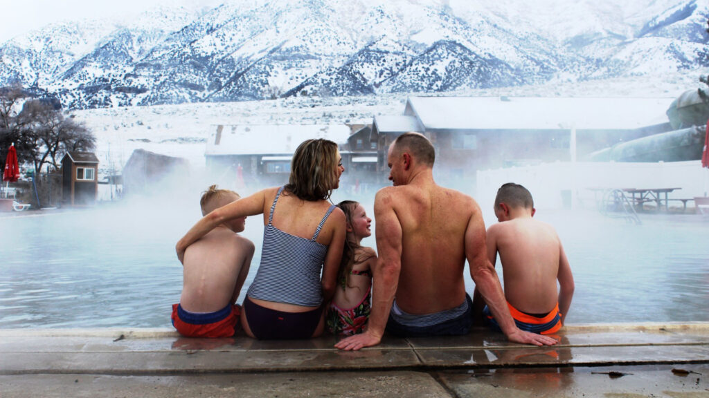 A family sitting together in the winter at crystal hot springs in Utah