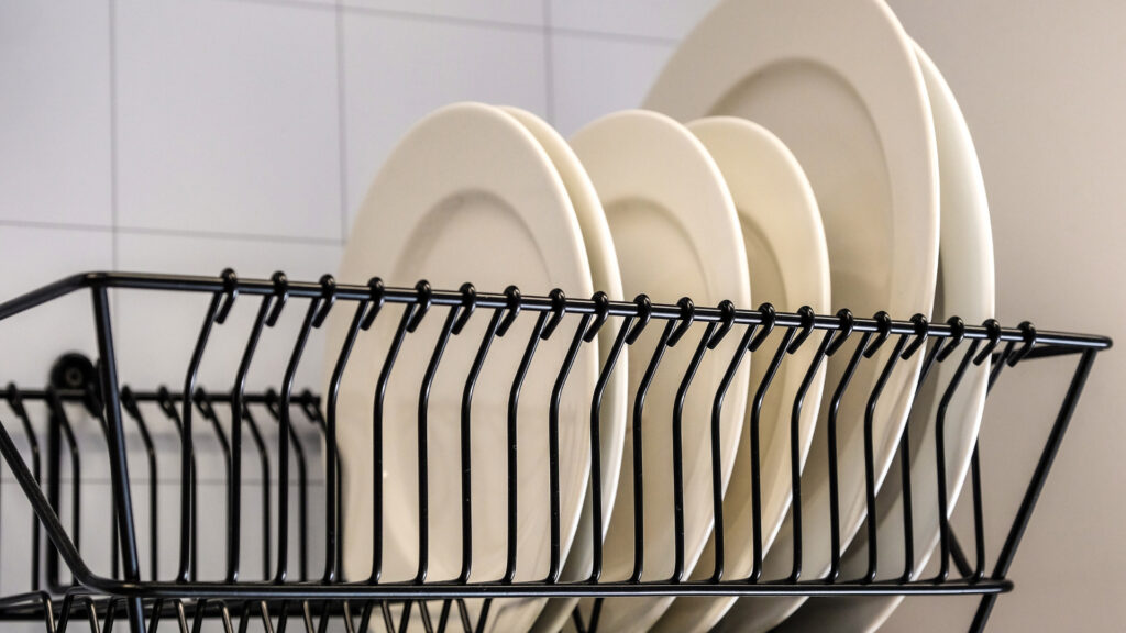 A drying rack over the sink with plates 