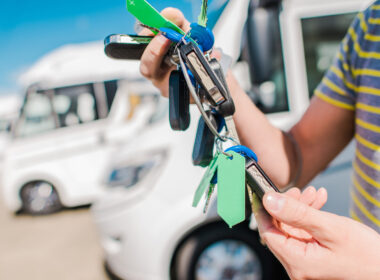 A person holding keys to their new RV at an RV dealership