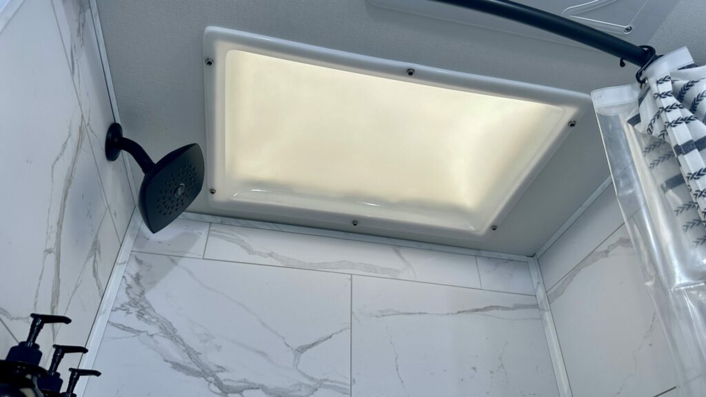 The skylight and upgraded RV shower head in our truck camper bathroom