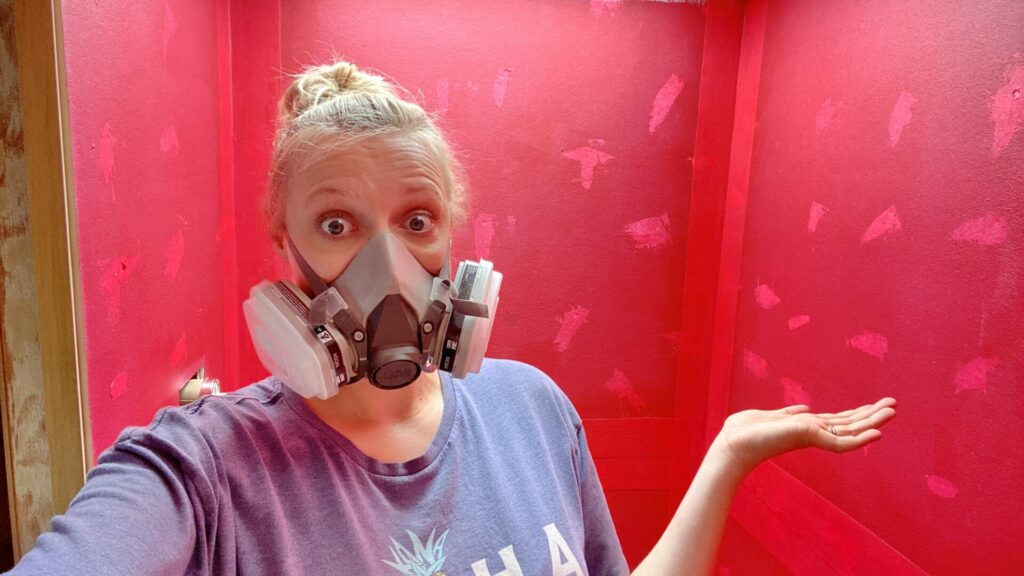Rae with a mask on after she finished painting the RedGard in the showering during our RV bathroom remodel  