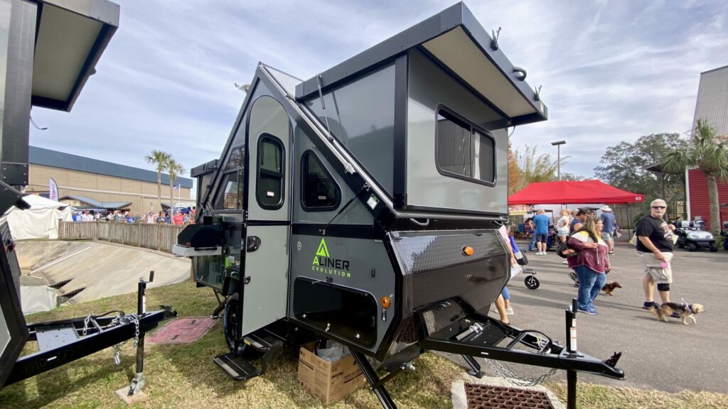 Outside of the Aliner Evolution at an RV show, a pop up camper with a bathroom