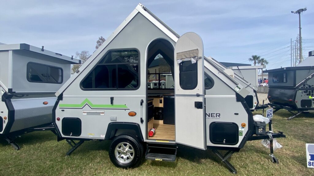 Outside of the Aliner LXE at an RV show, a pop up camper with a bathroom