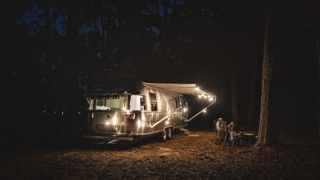 An Airstream RV parked outside in the woods