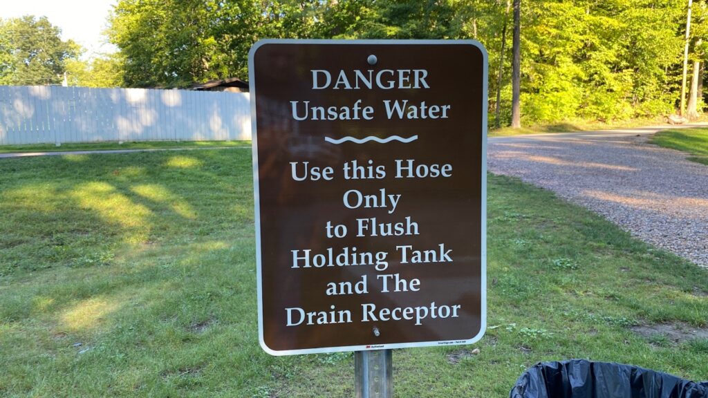 A sign at an RV park dump station warning people to only use the hose provided for flushing your black tank 