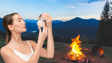 A woman spraying on campfire spray by a lit campfire