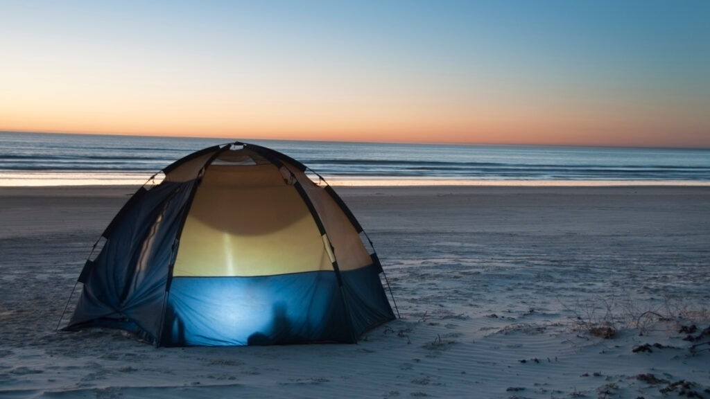 A tent set up on the beach following these tips to staying cool while camping in the summer
