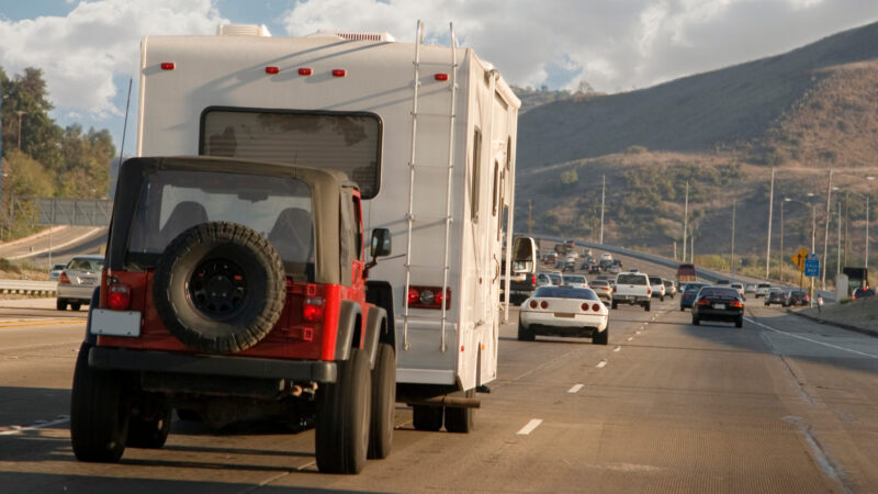 A jeep being flat towed by an RV