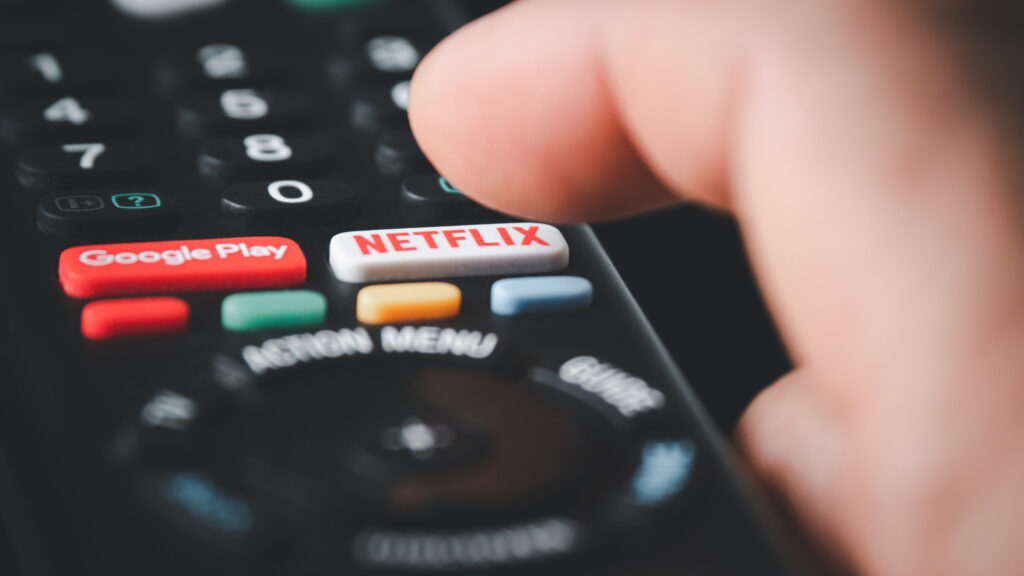Close up of a person clicking the Netflix button on the remote