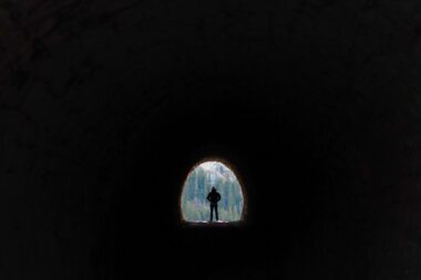 Man standing at end of tunnel