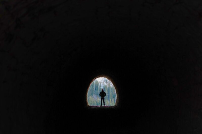 Man standing at end of tunnel