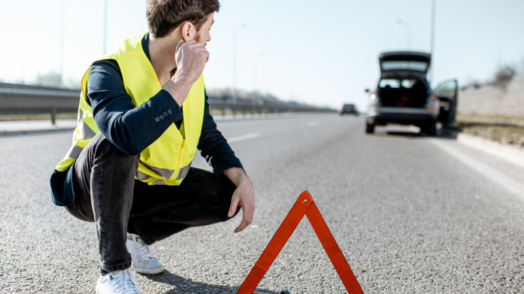 A person on the side of the road waiting for roadside assistance 