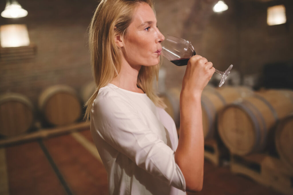 Woman tasting wine in winery cellar