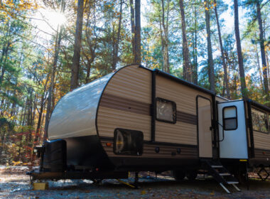 A travel trailer with a damaged a-frame parked out in the woods