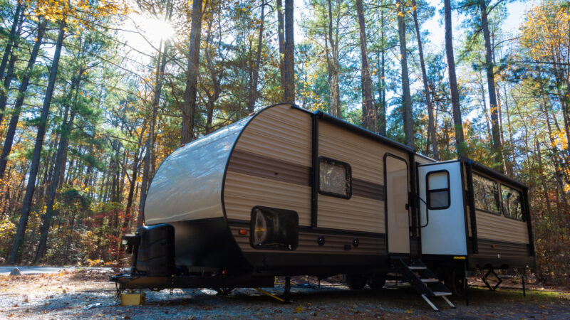A travel trailer with a damaged a-frame parked out in the woods