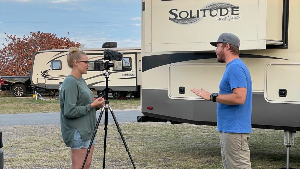 Rae and Jason, RV YouTubers, outside filming a video in an RV park 