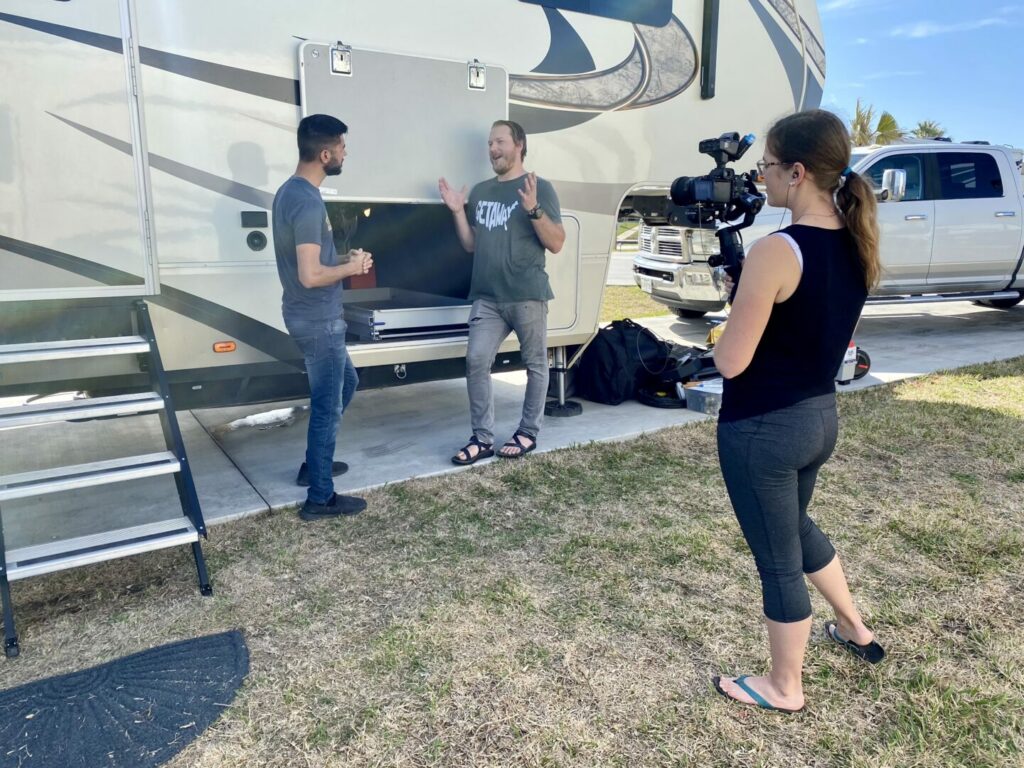 RV YouTubers recording a video in front of a fifth wheel RV 