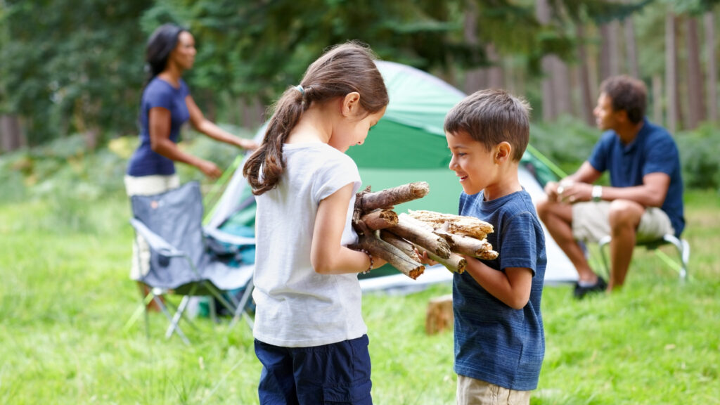 Kids grabbing firewood while camping with their parents
