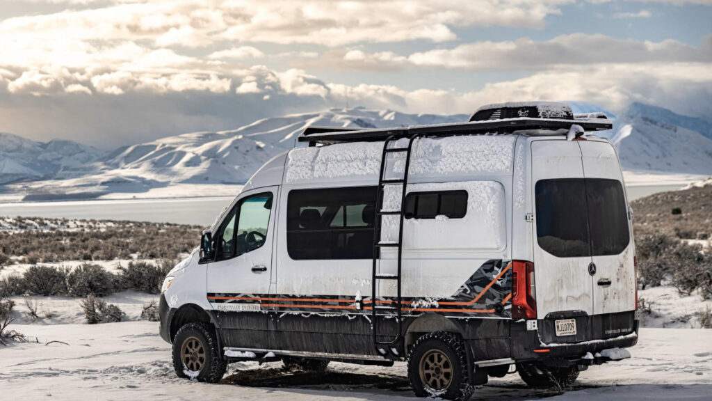 A storyteller overland van parked by the mountains in the snow