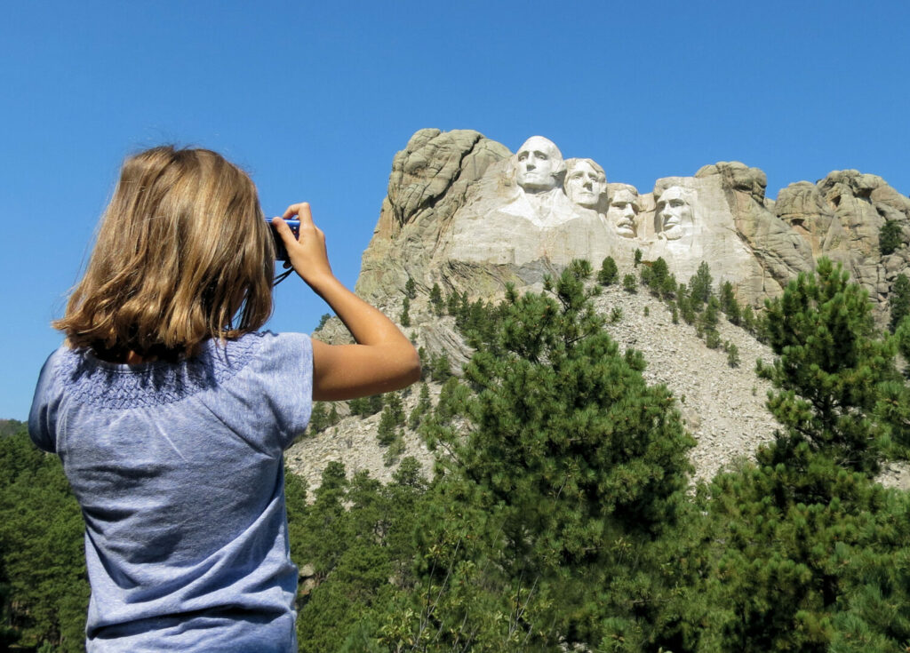 Little girl taking a photo of Mt. Rushmore