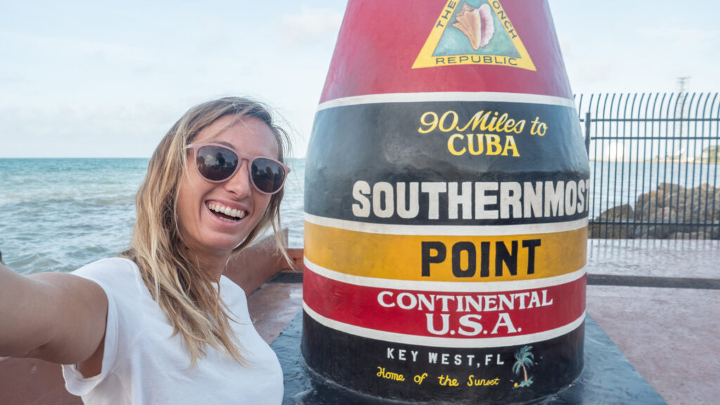 A woman taking a selfie with the southernmost point buoy