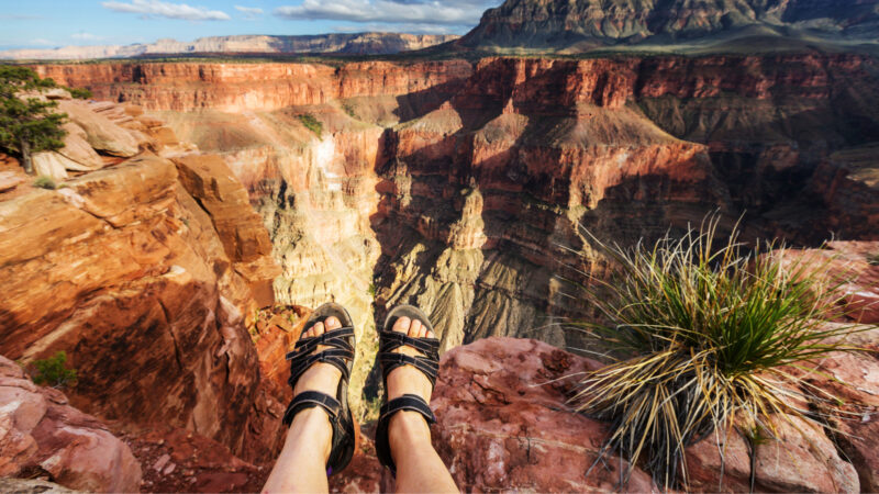 Close up of someone's feet sitting on the edge of the grand canyon