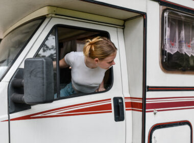 A woman looking back to back out of a spot while driving an RV